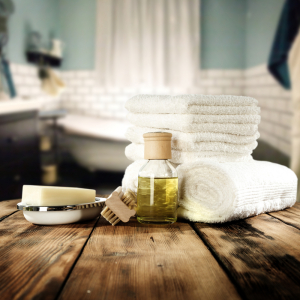 stack of towels, a bottle of oil, and other spa essentials for home