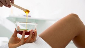 a woman holding a small bowl with hot brazilian wax