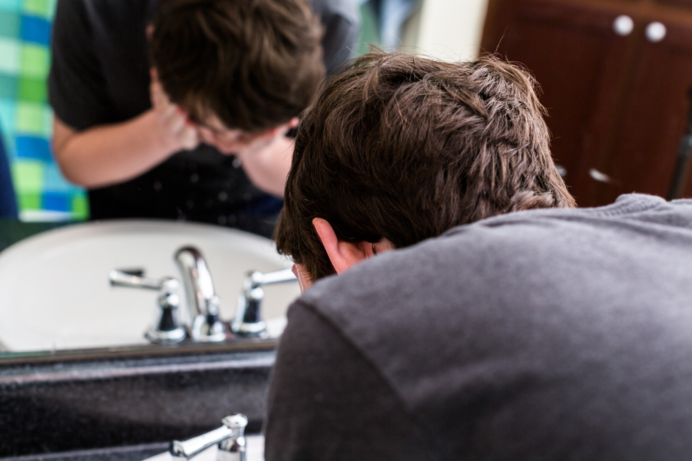 Teenage boy washing his face